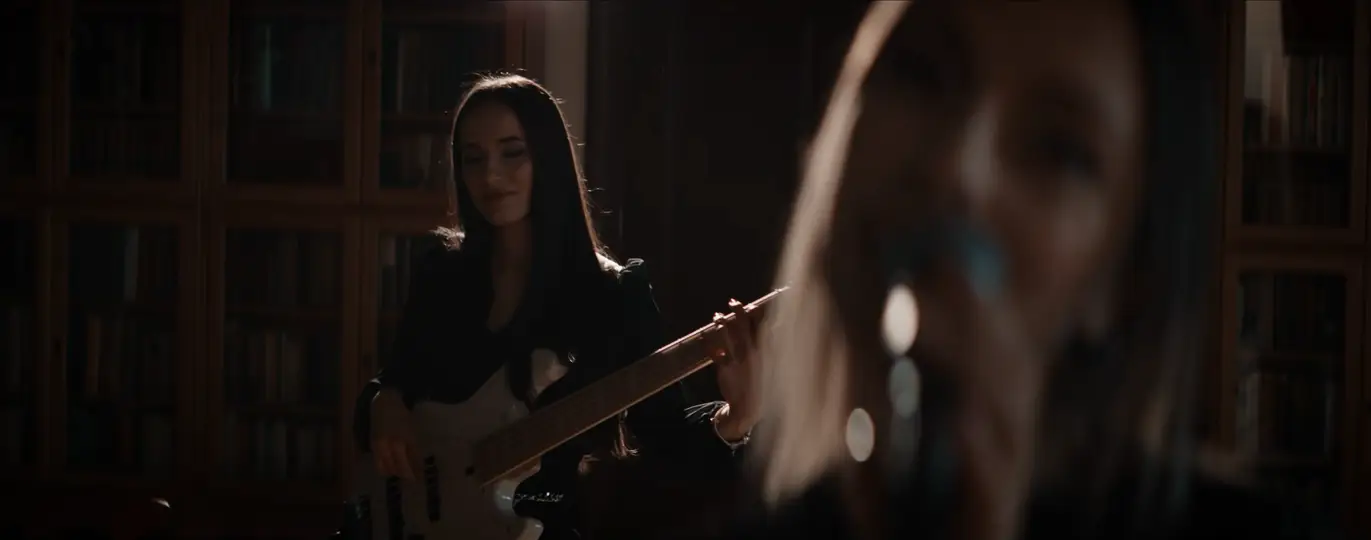 Jákli Zsófi basszusgitárral a könyvtárszobában.