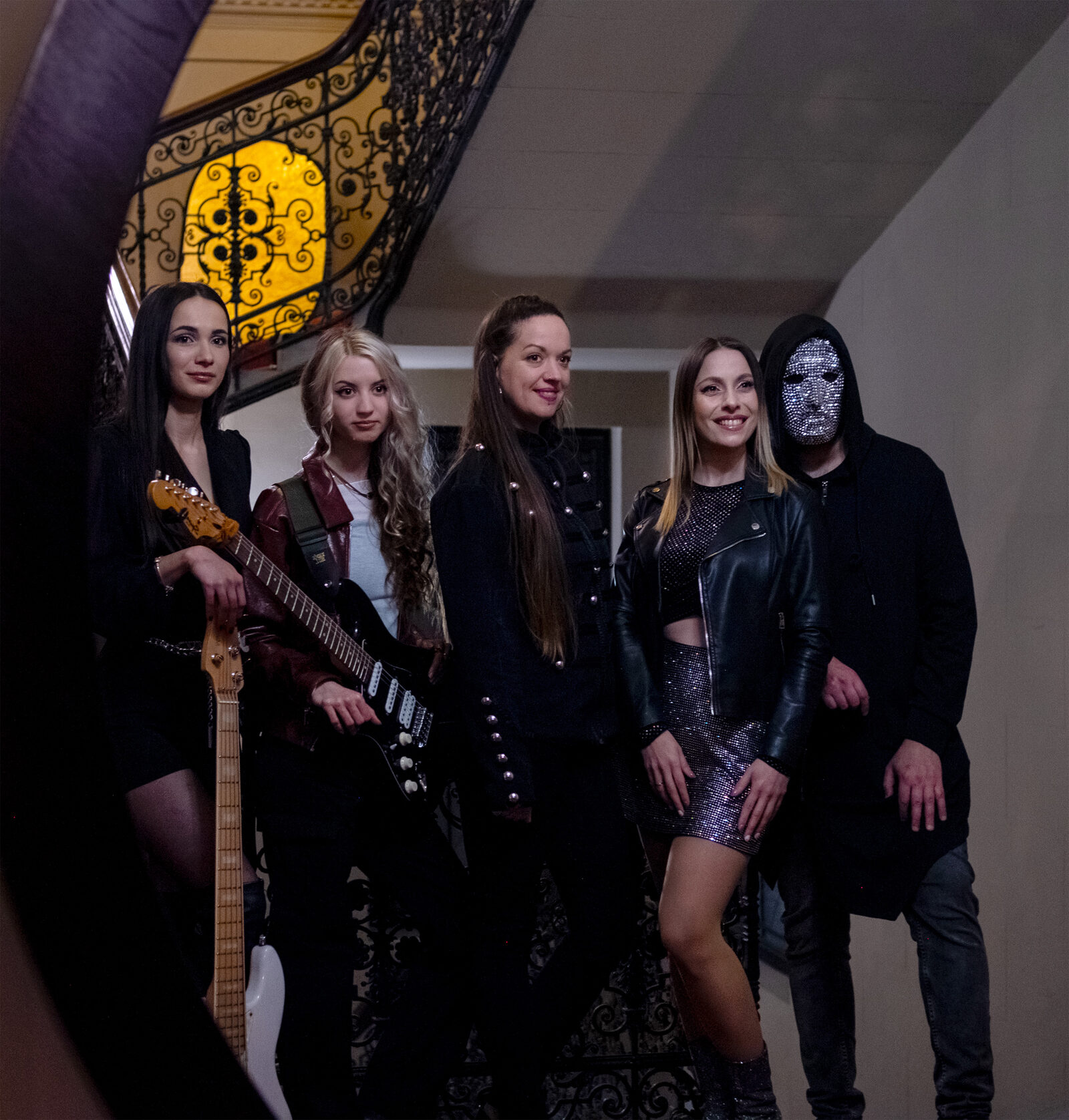 Az ASTOREA öt tagja egy villa díszes lépcsőjén, mögöttük borostyánsárgán világító kovácsoltvas ablak; jobbra Amison kristálymaszkban.